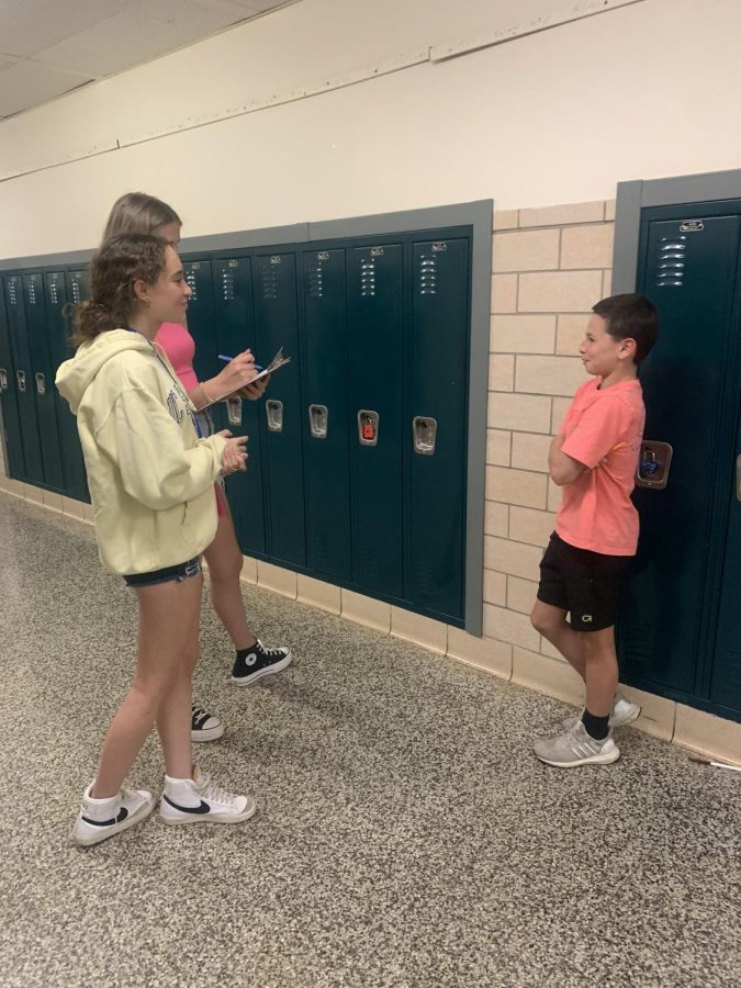 These journalism students are using antiquated clipboards and paper to interview students in the hallway.