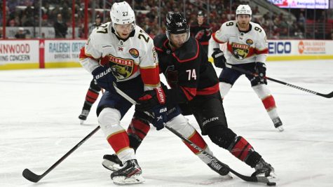 Carolina defenseman Jacob Slavin and Florida center Eetu Luostarinen battle for the puck.