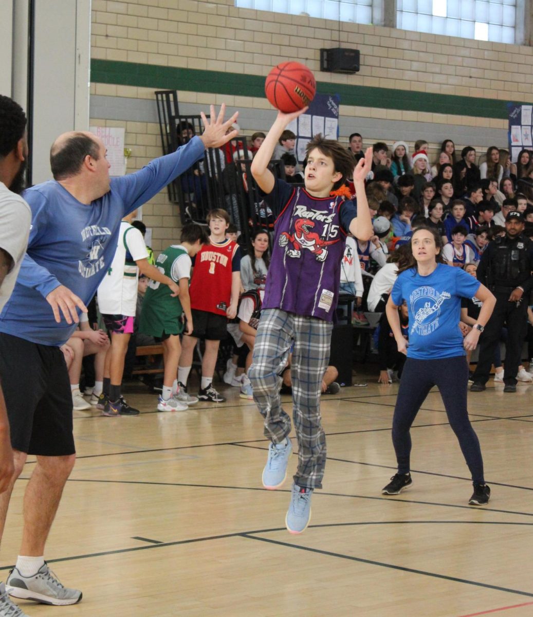 Eighth grader Aston Cerminara takes a shot against Mr. Ryan Belline during the beloved student teacher basketball game. 